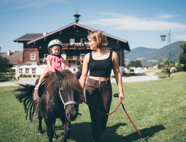 Kind und Reiterin beim Ponyreiten am Hof © Lorenz Masser Fotografie