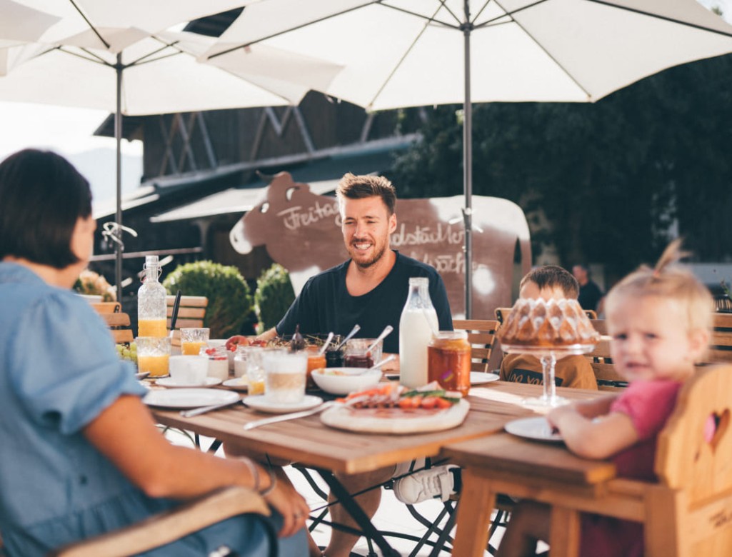 Familie genießt ein gemeinsames Mittagessen im Freien im Obersulzberggut in Radstadt, umgeben von Natur © Lorenz Masser Fotografie