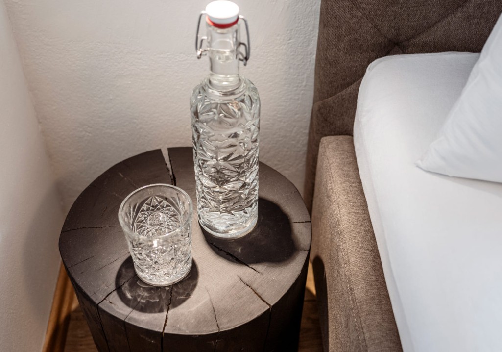 Wasserflasche und Gläser auf Nachttisch im Schlafzimmer des Obersulzbergguts in Radstadt © Lorenz Masser Fotografie