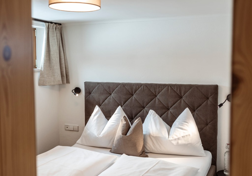 Second cozy bedroom with pillow arrangement at Obersulzberggut in Salzburg © Lorenz Masser Photography